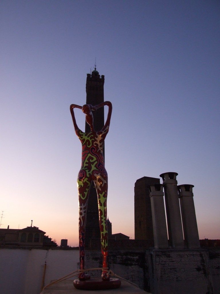 Una scultura di una mostra Case Aperte con lo sfondo della Torre degli Asinelli. Simbolo di Bologna